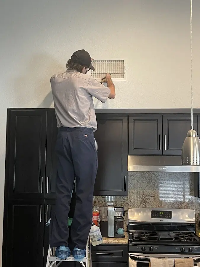 Technician inspecting an air vent during HVAC service in Kennett